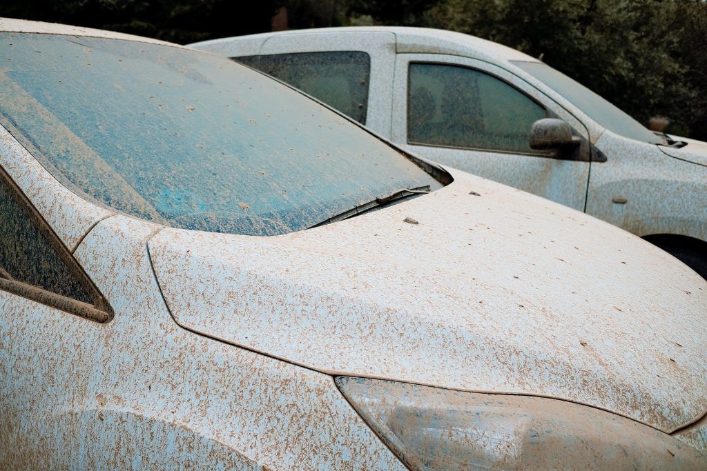 two dirty cars covered in mud, parked next to each other
