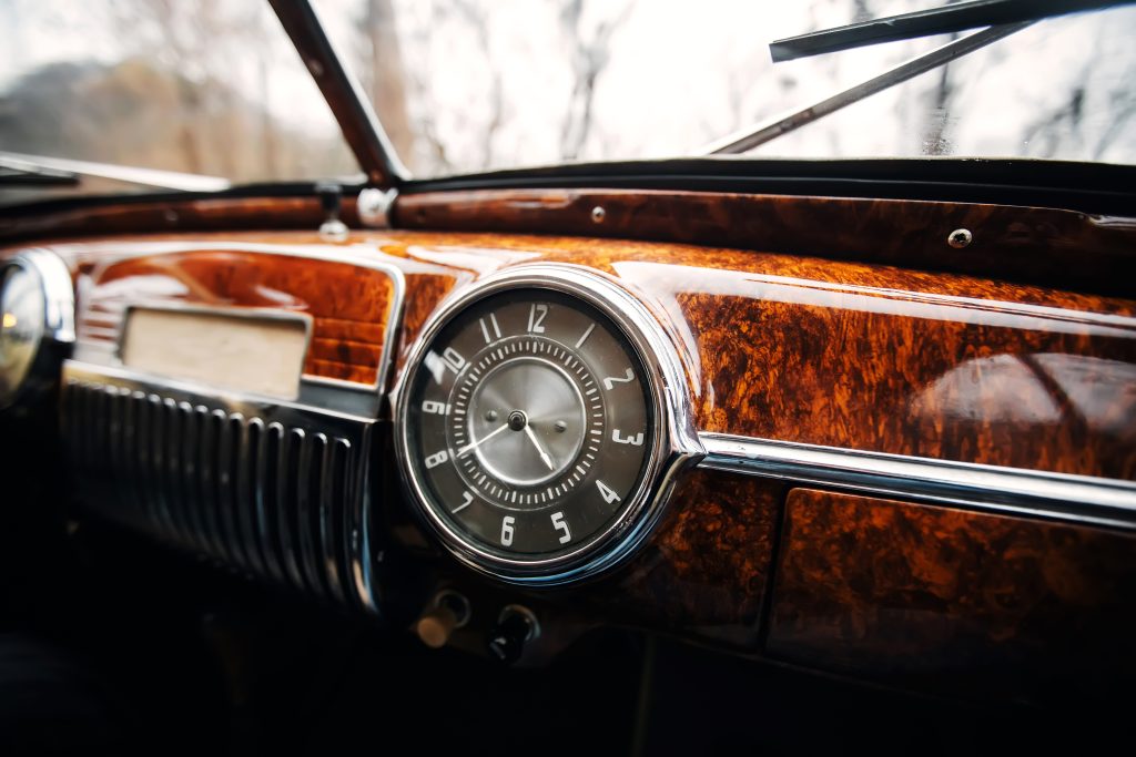dashboard of vintage car displaying a retro clock prominently